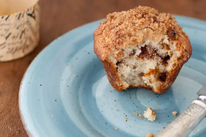 Close up of a cinnamon muffin on a blue plate with a big bite out of it