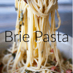 Closeup of two wooden spoons pulling out heaping strands of spaghetti with brie sauce from a big green pot