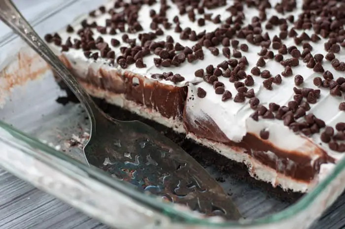 glass casserole dish with partially cut out chocolate lasagna pieces and a silver spatula