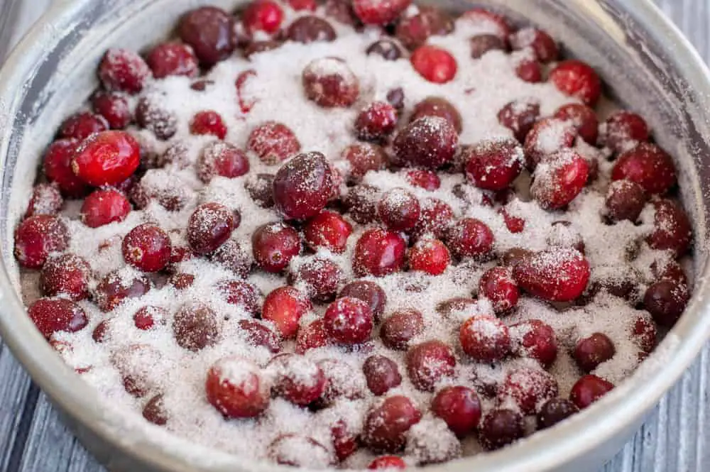 Silver cake pan filled to the rim with fresh cranberries and lots of sugar and spices