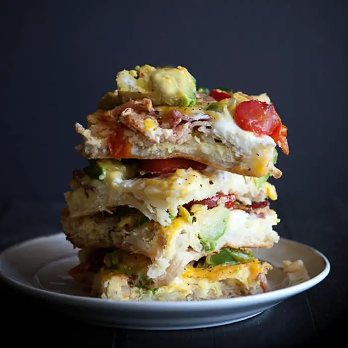 Side view of slices of breakfast casserole stacked on top of each other on a white plate