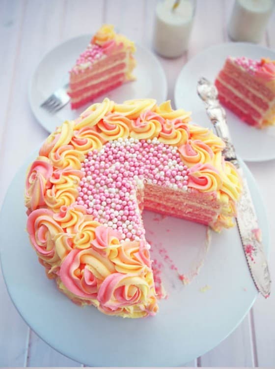 Pink ombre cake layers with yellow and pink frosting and large pink and white beaded candies on top