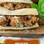 3 long meatball sub sandwiches lined up on a wooden platter with a beige napkin and text that says Broken Meatball Sandwich