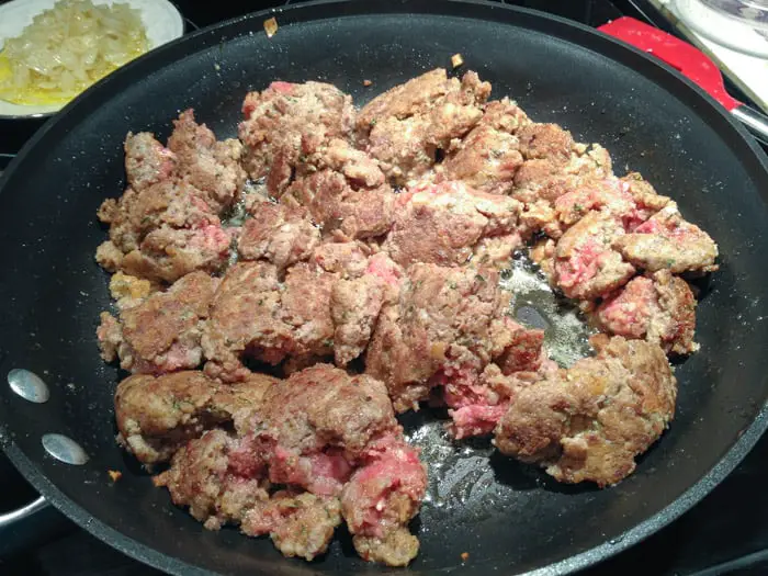 nonstick skillet with partially cooked broken meatballs