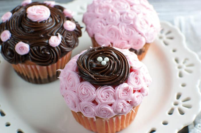 3 strawberry and fudge cupcakes on a white lattice-edged plate