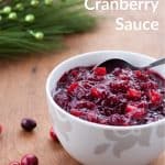 White bowl filled with cranberry sauce and a silver spoon with text that says Homemade Cranberry Sauce - Ready in 20 minutes