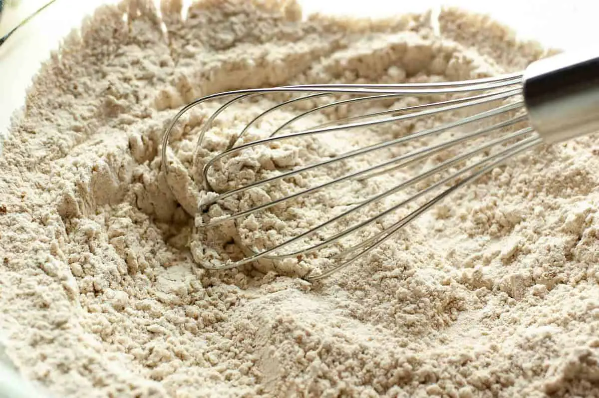 Silver whisk mixing flour with pumpkin spices