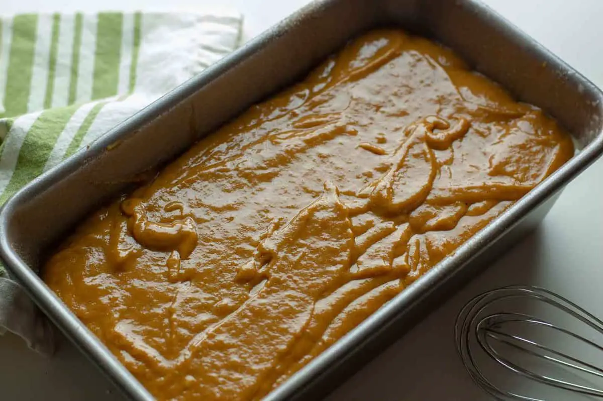 pumpkin banana bread mixture poured and ready to bake with a green striped napkin on a table
