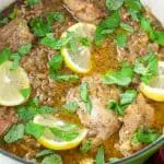 Seared chicken thighs and lemon slices with chopped basil in a green stock pot