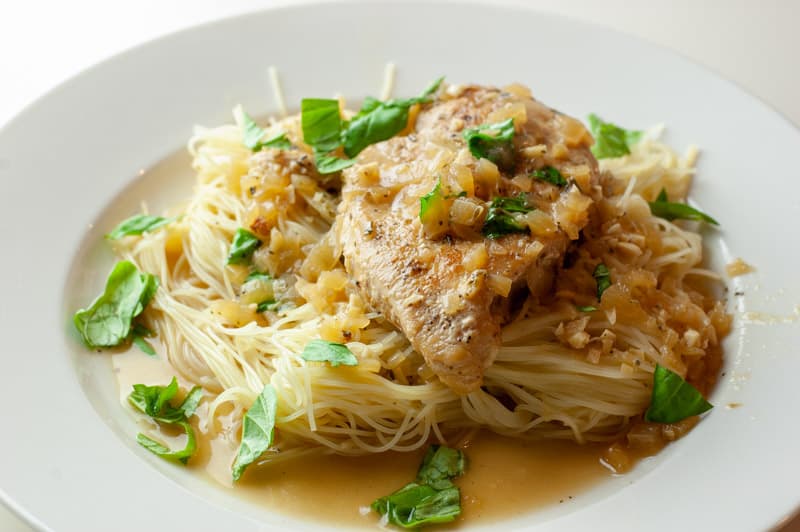 Angel hair pasta topped with lemon garlic chicken breast and chopped fresh basil