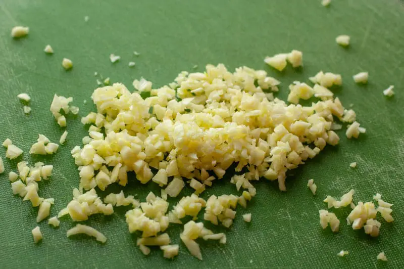 Minced garlic on a green cutting board