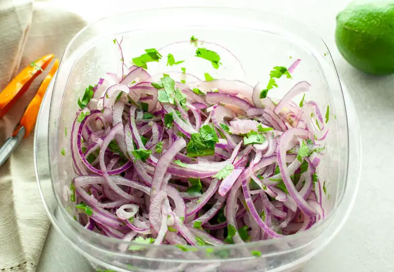 Salsa Criolla in a tupperware ready to store in the fridge while it marinates