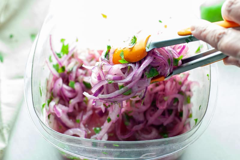 Mixing together the marinated onions for salsa criolla