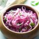 brown wooden bowl filled with thinly sliced marinated red onions