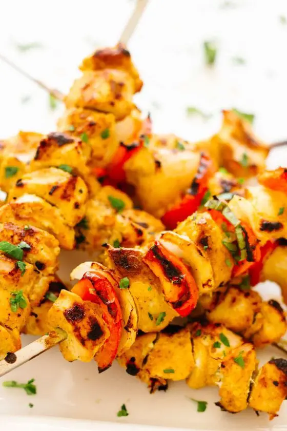 pieces of Tandoori chicken, onion, and red pepper on wooden skewers