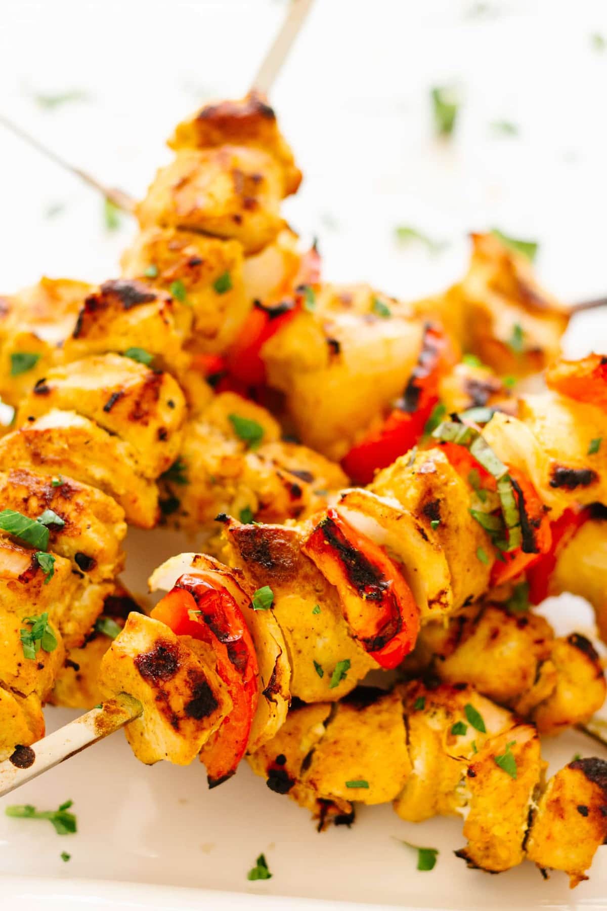 pieces of Tandoori chicken, onion, and red pepper on wooden skewers