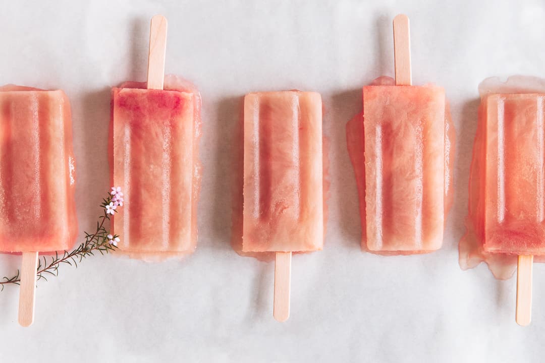 5 alternating peachy pink popsicles on parchment paper